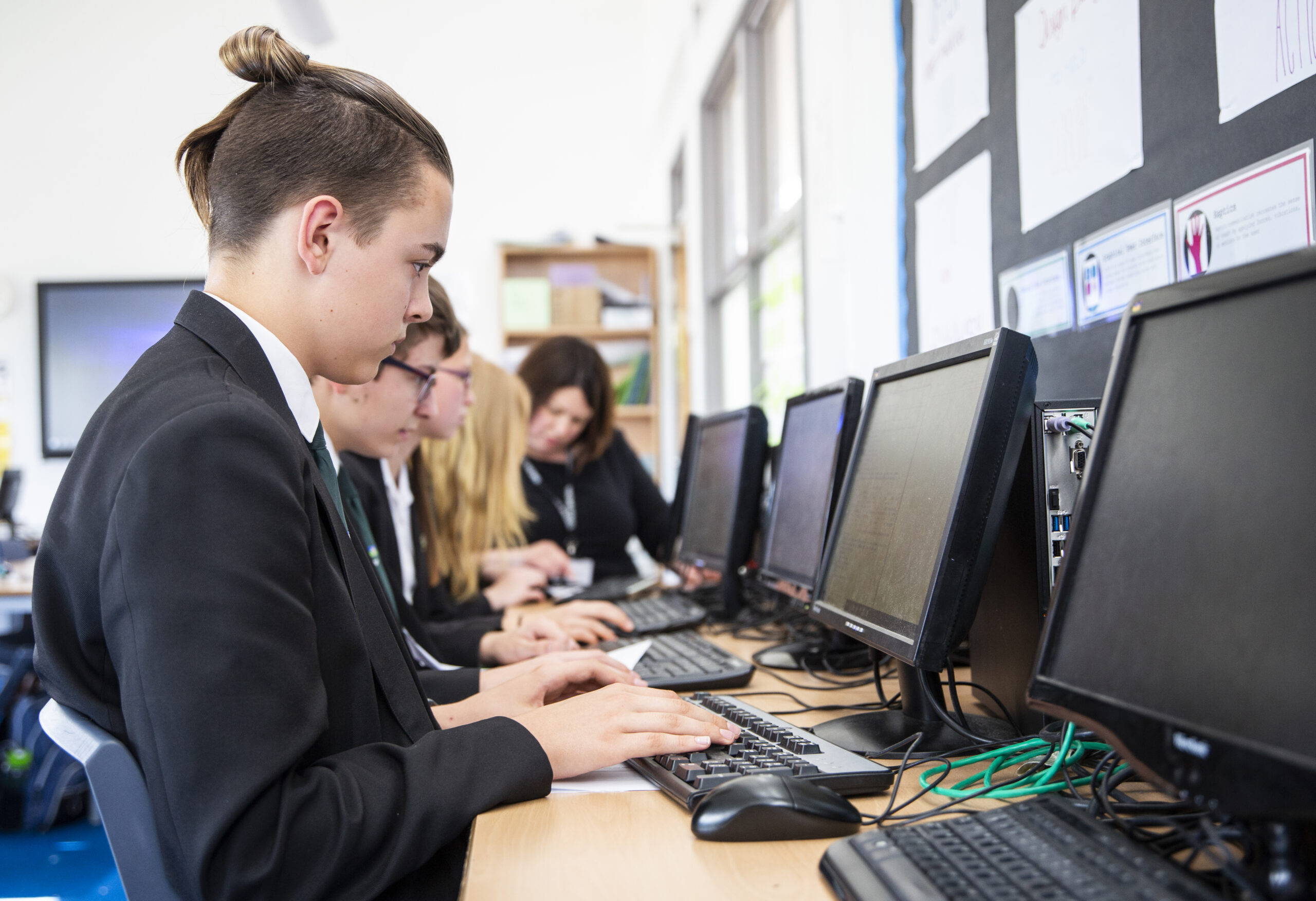 a teenage boy does coding during a computer science lesson.