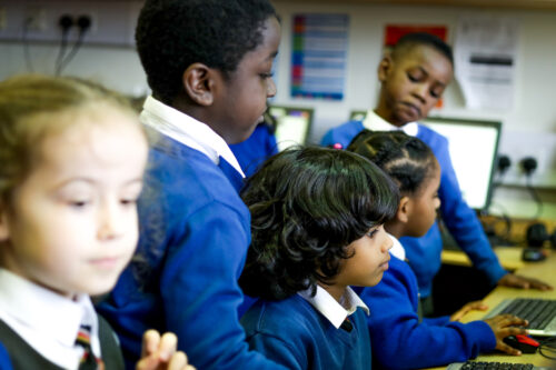 Young learners at computers in a classroom.